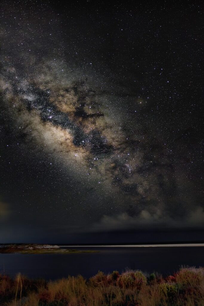 Milky way galaxy arches over a serene night landscape.