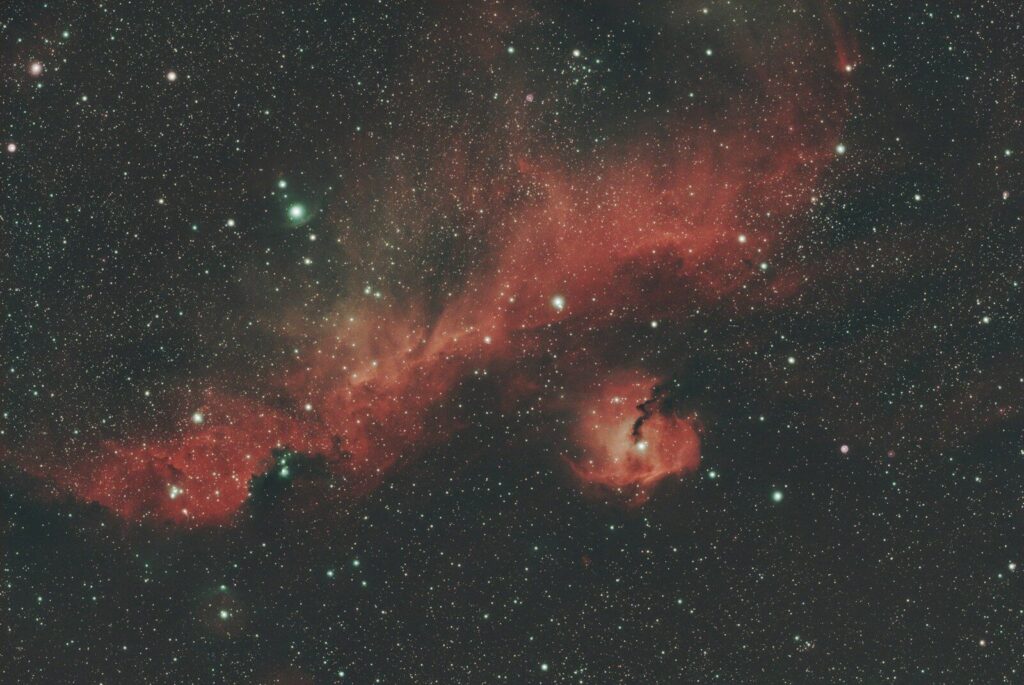 Vast cosmic landscape with glowing red nebulae and countless stars.