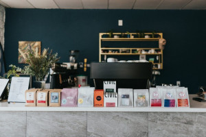 Coffee bags lined up on a white counter in a cafe with dark walls.