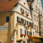 A yellow building with green shutters and red flowers in Regensburg, Germany.